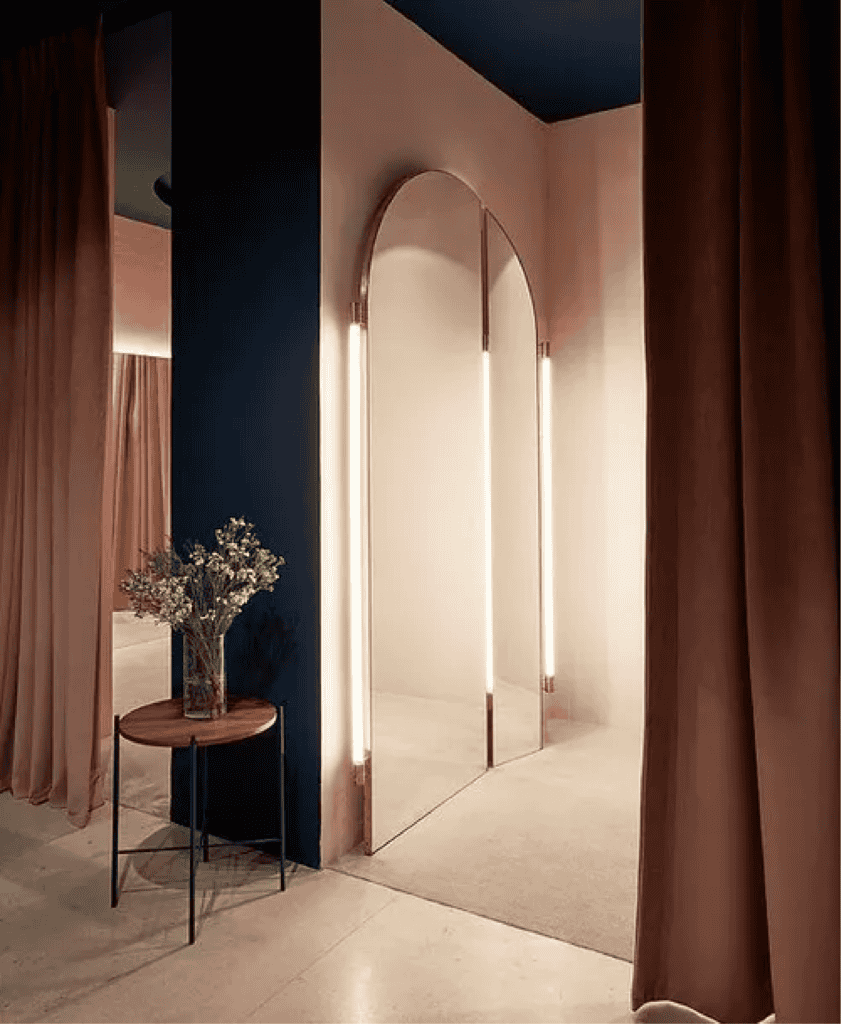 A well-lit fitting room with a curtain and mirror