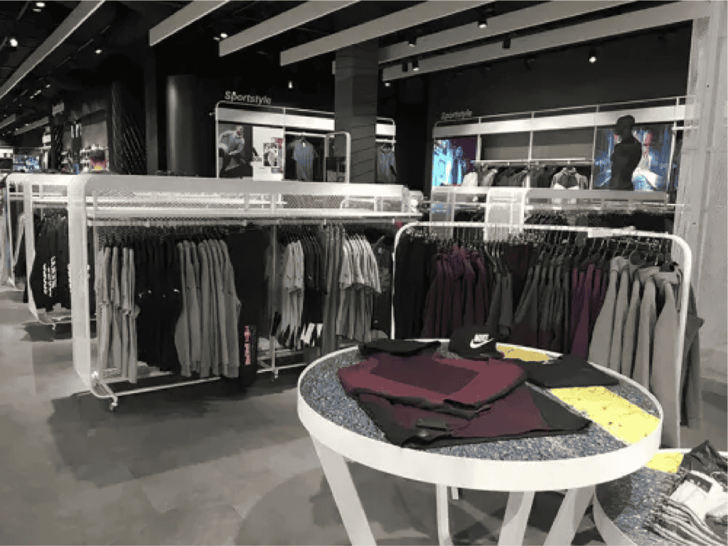 Indoor retail apparel display shows clothing hanging neatly from racks and folded on tables